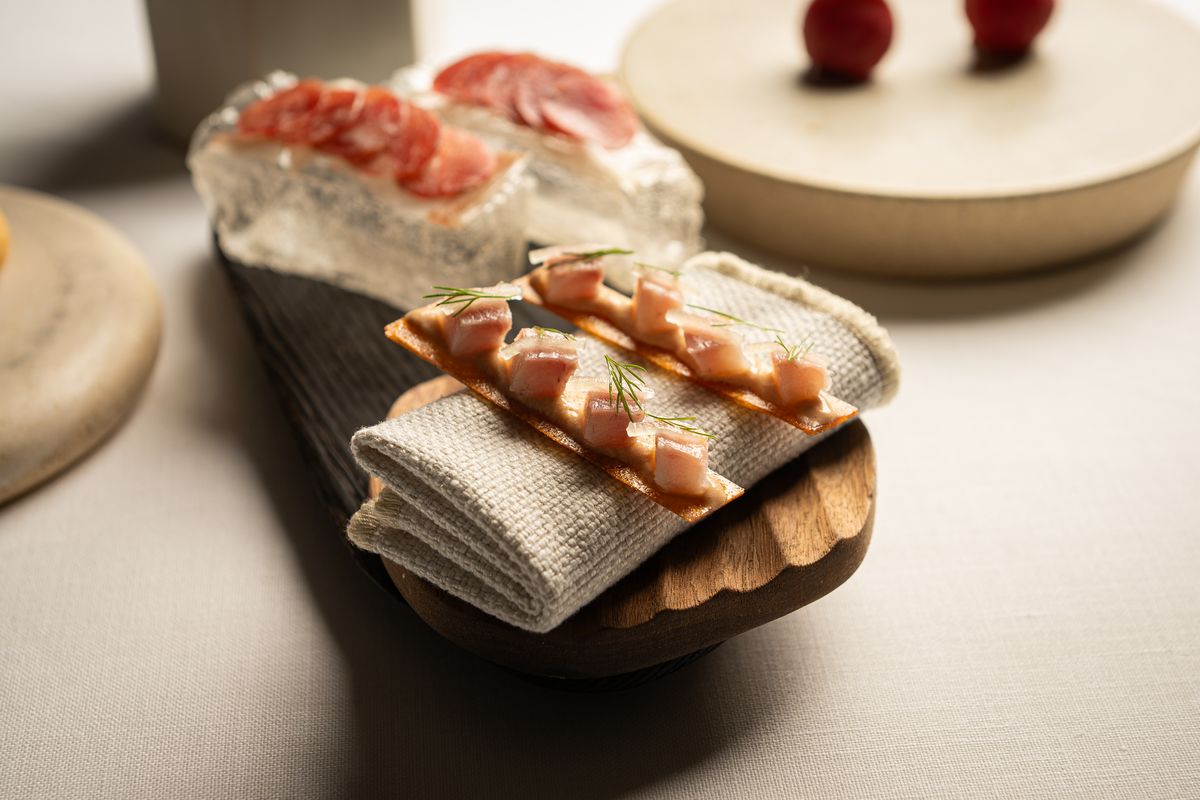 Pan de cristal con papada curada, en diagonal sobre una tabla de madera oscura