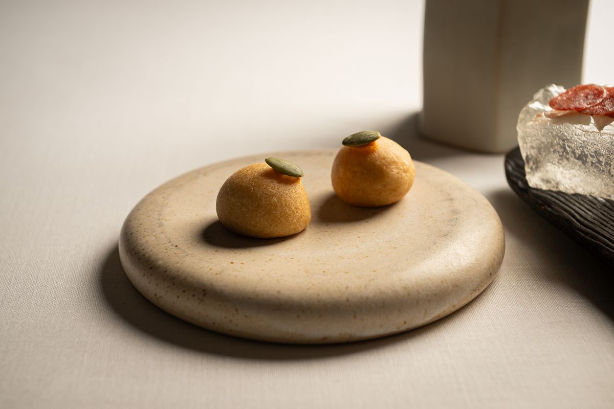 Buñuelos con pipa de calabaza sobre plato de piedra, aperitivo de Sol Post